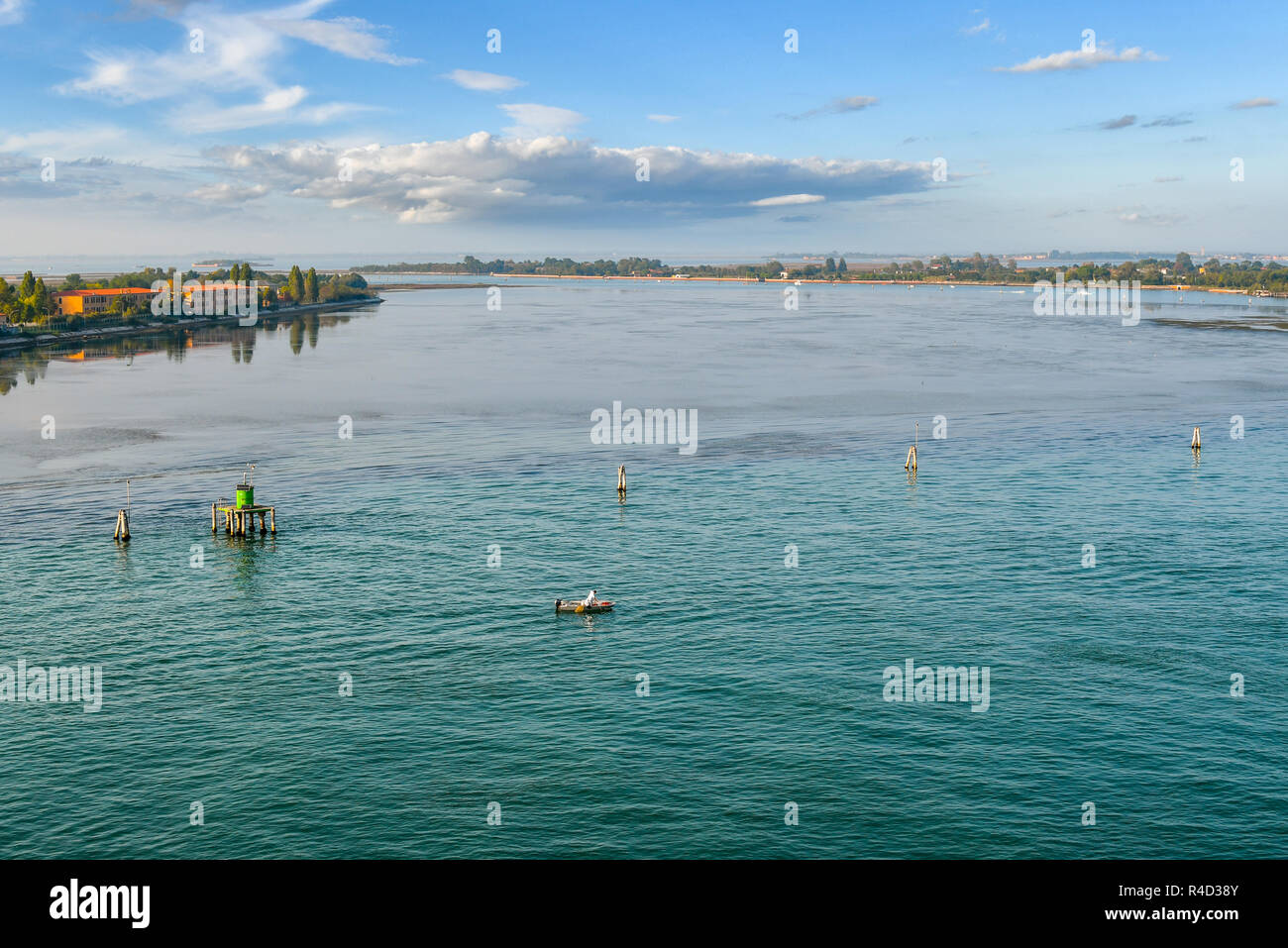 A fisherman in a small boat fishes off the coast of one of the outer islands near the lagoon of Venice, Italy. Stock Photo