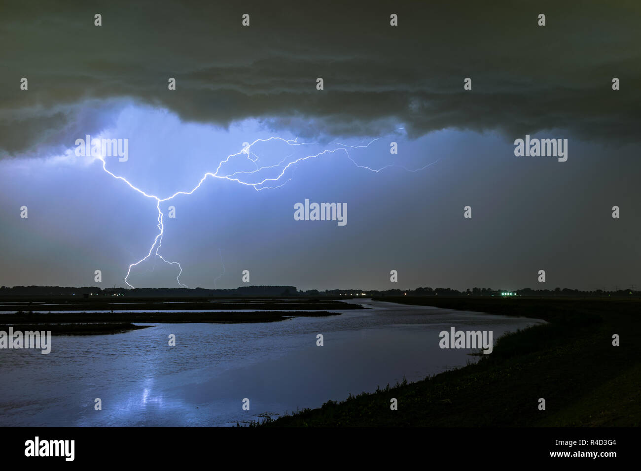 Horizontal and vertical lightning bolts from a severe thunderstorm over a lake in the western part of Holland. Stock Photo