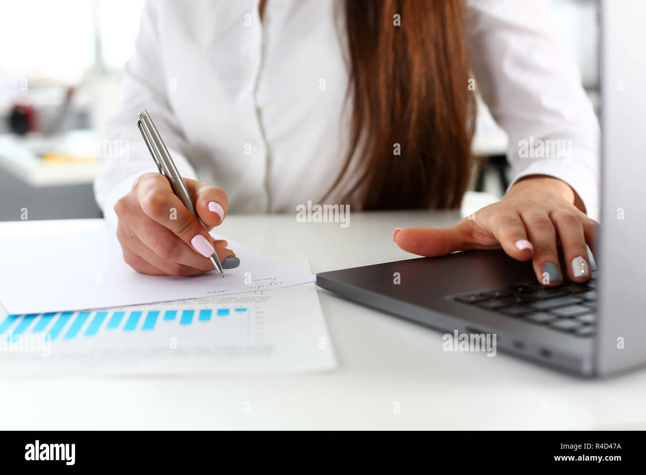 Female arms write with silver pen and type at laptop Stock Photo - Alamy