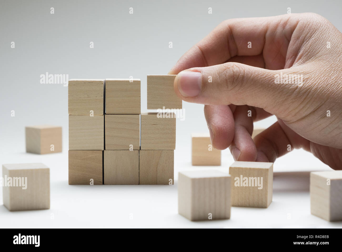 Hand stacking up wood cubes to build a complete 3x3 building Stock