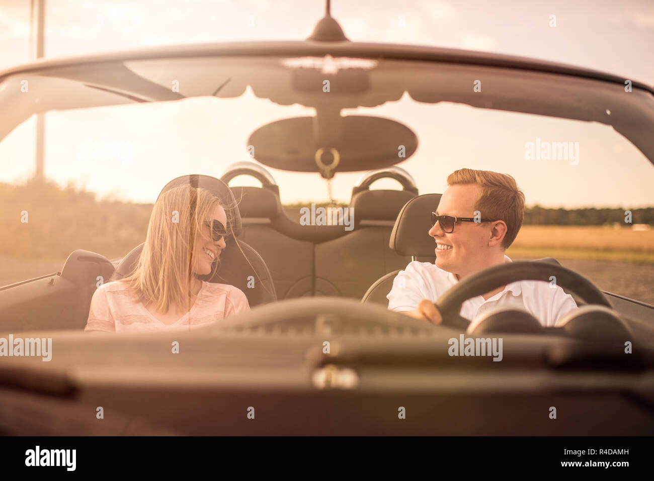 young loving couple in a convertible looks in love Stock Photo