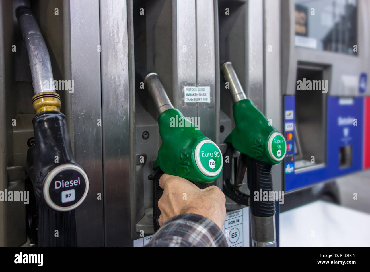 Man selecting petrol fuel pump nozzle at gas station for refueling his