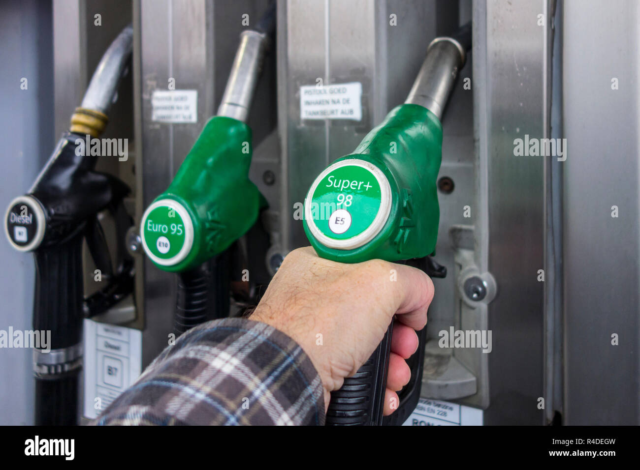 Man selecting petrol fuel pump nozzle at gas station for refueling his car in Europe Stock Photo