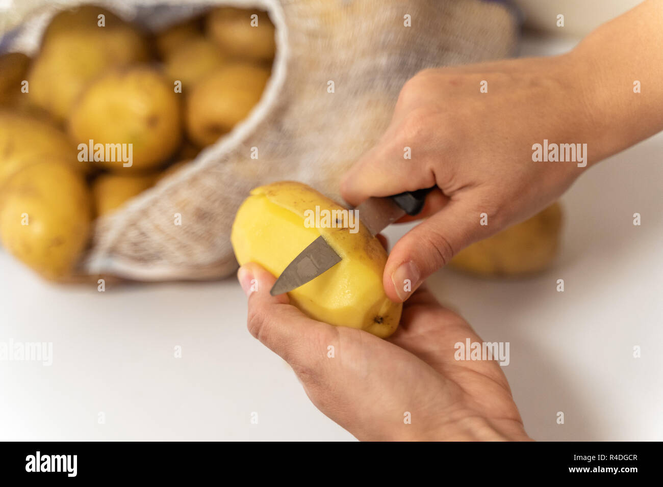 https://c8.alamy.com/comp/R4DGCR/womans-hands-with-small-kitchen-knife-potatoes-peeling-bag-with-unpeeled-potatoes-R4DGCR.jpg