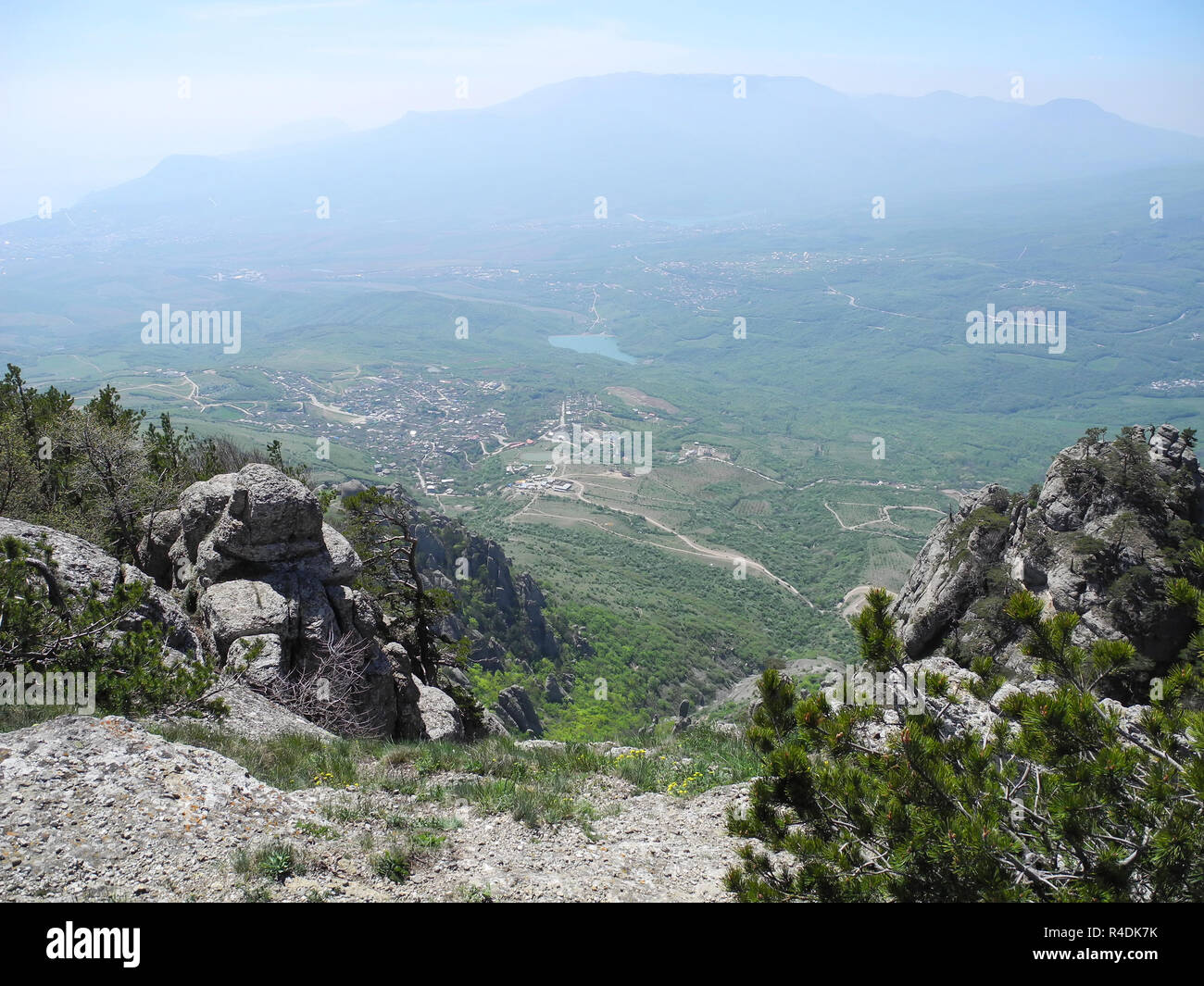 Beautiful mountain landscape with top view of a distant valley with lake. Distant mountain plateaus in a blue haze. Crimean mountains Stock Photo