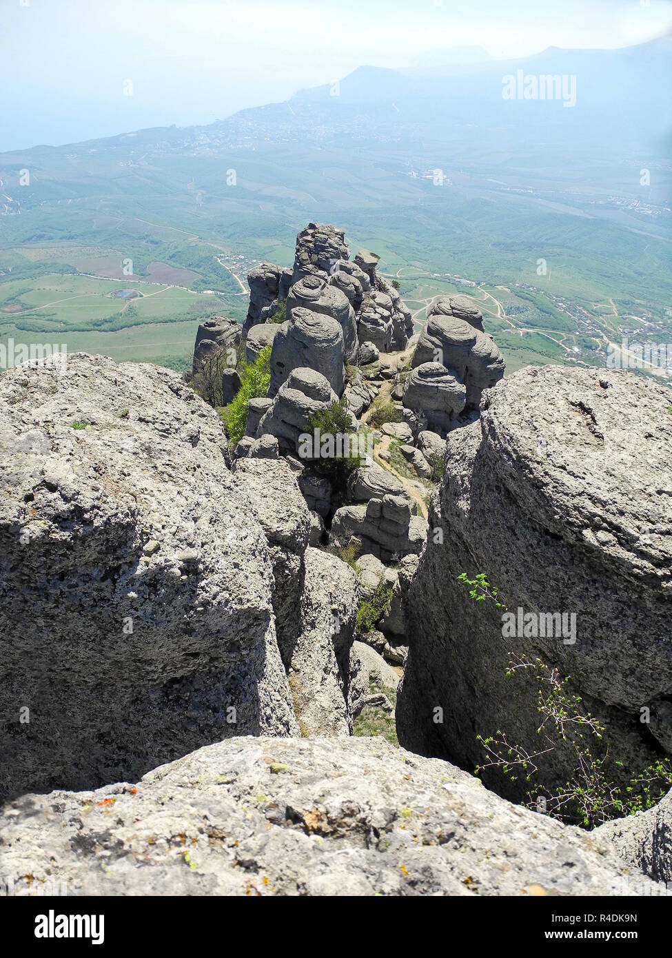 Beautiful mountain landscape with rounded rocks. Top view of the inhabited valley. Distant mountain plateaus in a blue haze and sea far below on the h Stock Photo