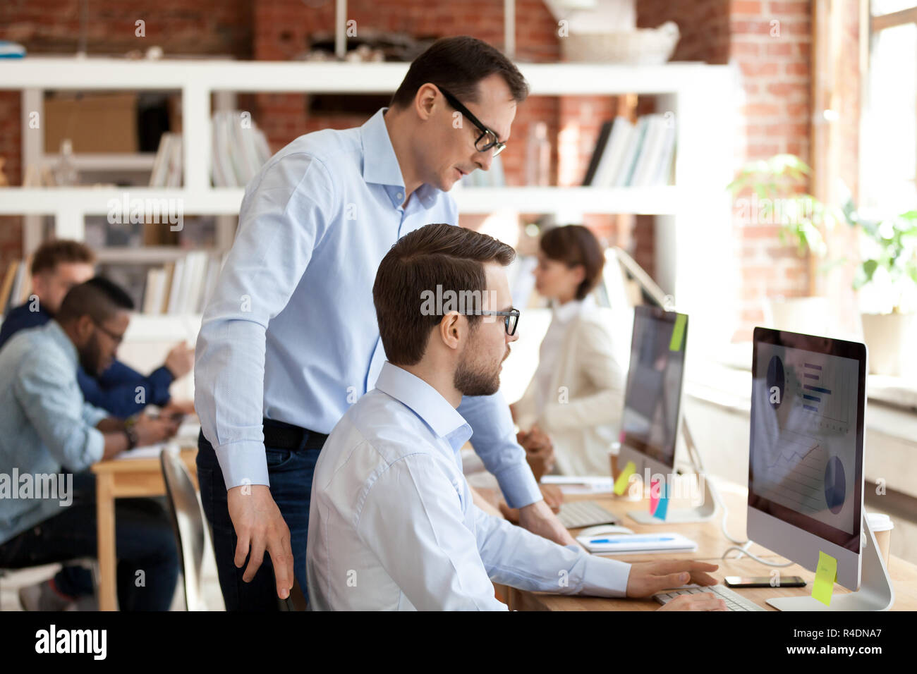 Middle aged mentor helping employee with computer work  Stock Photo