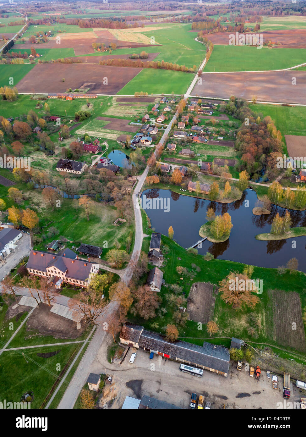 Aerial Drone Photograph of a  Village Surrounded with  Meadows  in Beautiful Spring Colours in Evening with Sunset Over it Stock Photo