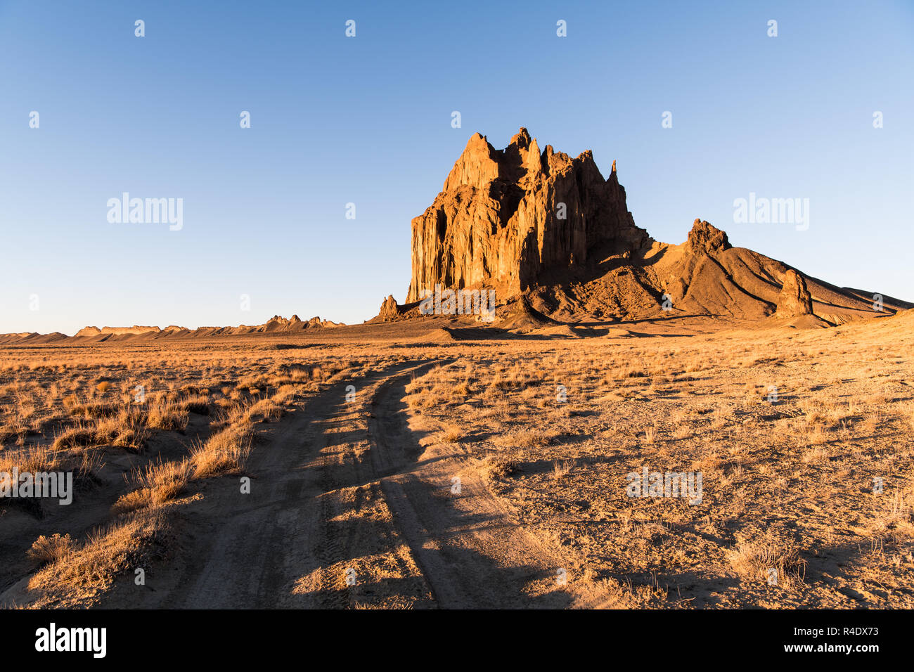 Road curving through a vast landscape to the rock formation of Shiprock