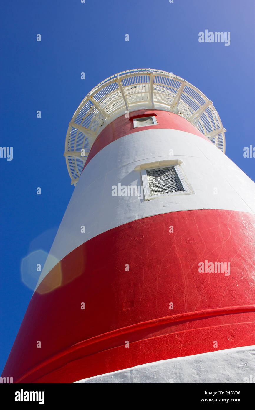 Close up image of a Red and White Lighthouse looking upwards to a blue sky background Stock Photo