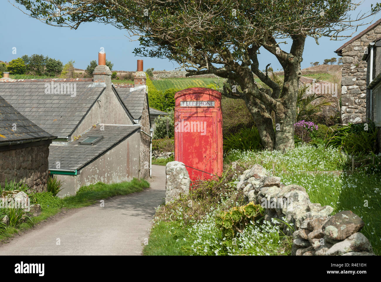 Middle Town on St Martin's, Isles of Scilly, with flowers and traditional red phone box on a sunny spring day. Stock Photo