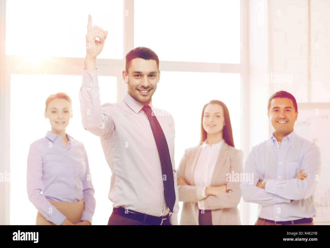 smiling businessman in office with team on back Stock Photo