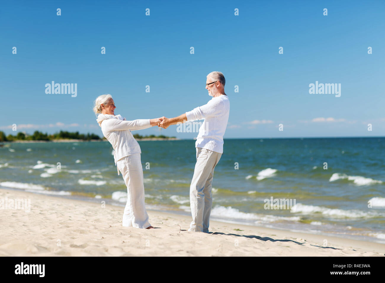 happy senior couple holding hands on summer beach Stock Photo - Alamy