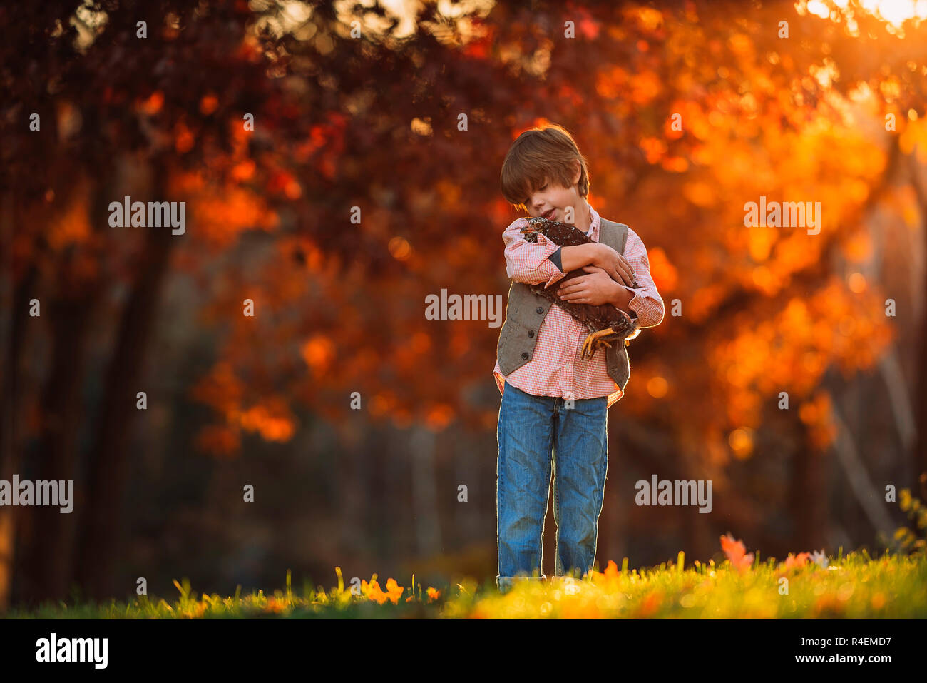 Boy standing outdoors cuddling a chicken, United States Stock Photo