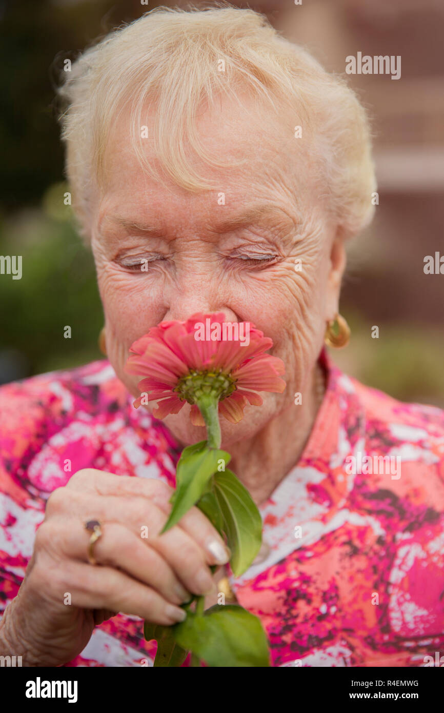 Senior Woman Smelling Flower, Eyes Closed, Close-Up Stock Photo