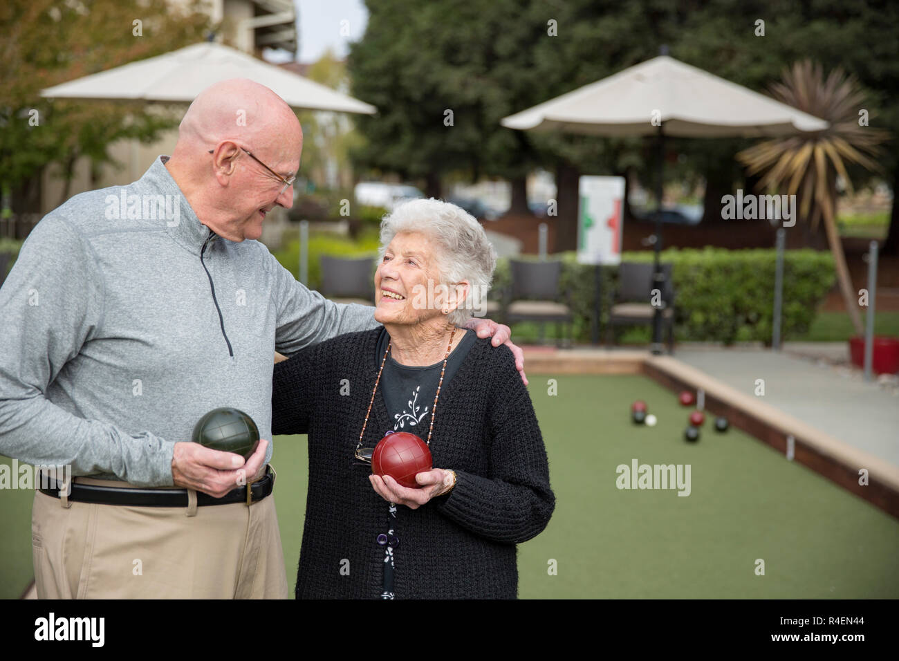 Senior Couple Looking Each Other While Holding Bowling Balls Stock Photo