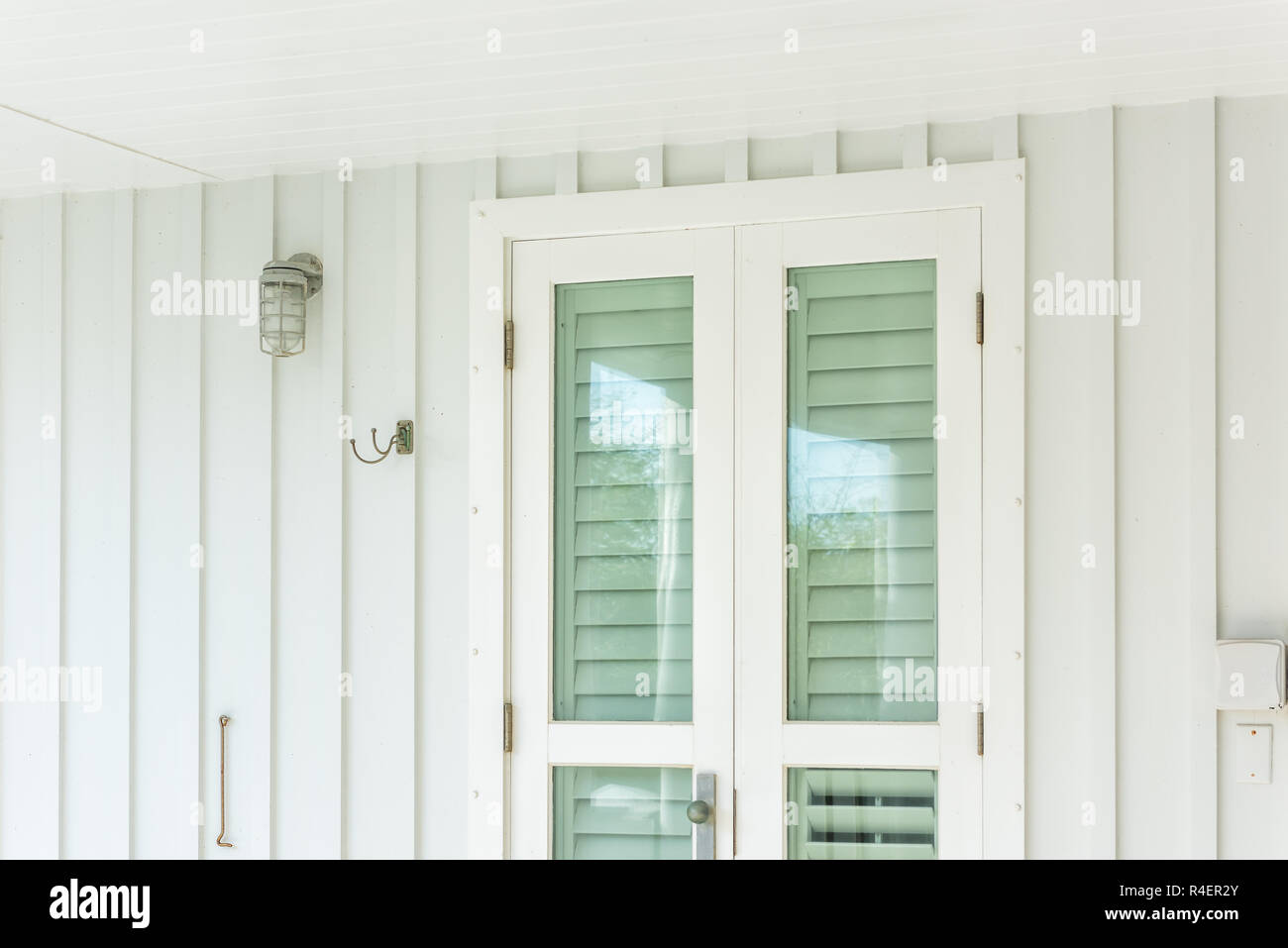 Pastel green colorful hurricane window shutters architecture open exterior of house in Florida beach home apartment building during day entrance, glas Stock Photo