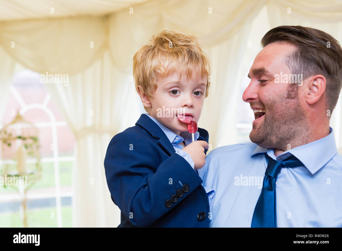Boy with his tongue out licking a lollipop at Fishlake Mill wedding reception in a marquee. Stock Photo