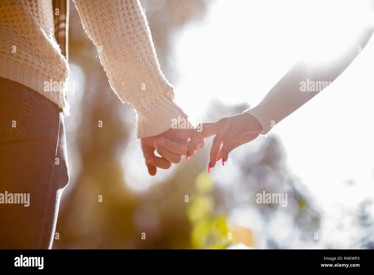 Cute couple in love is holding hands outdoors on a big sunlight ...