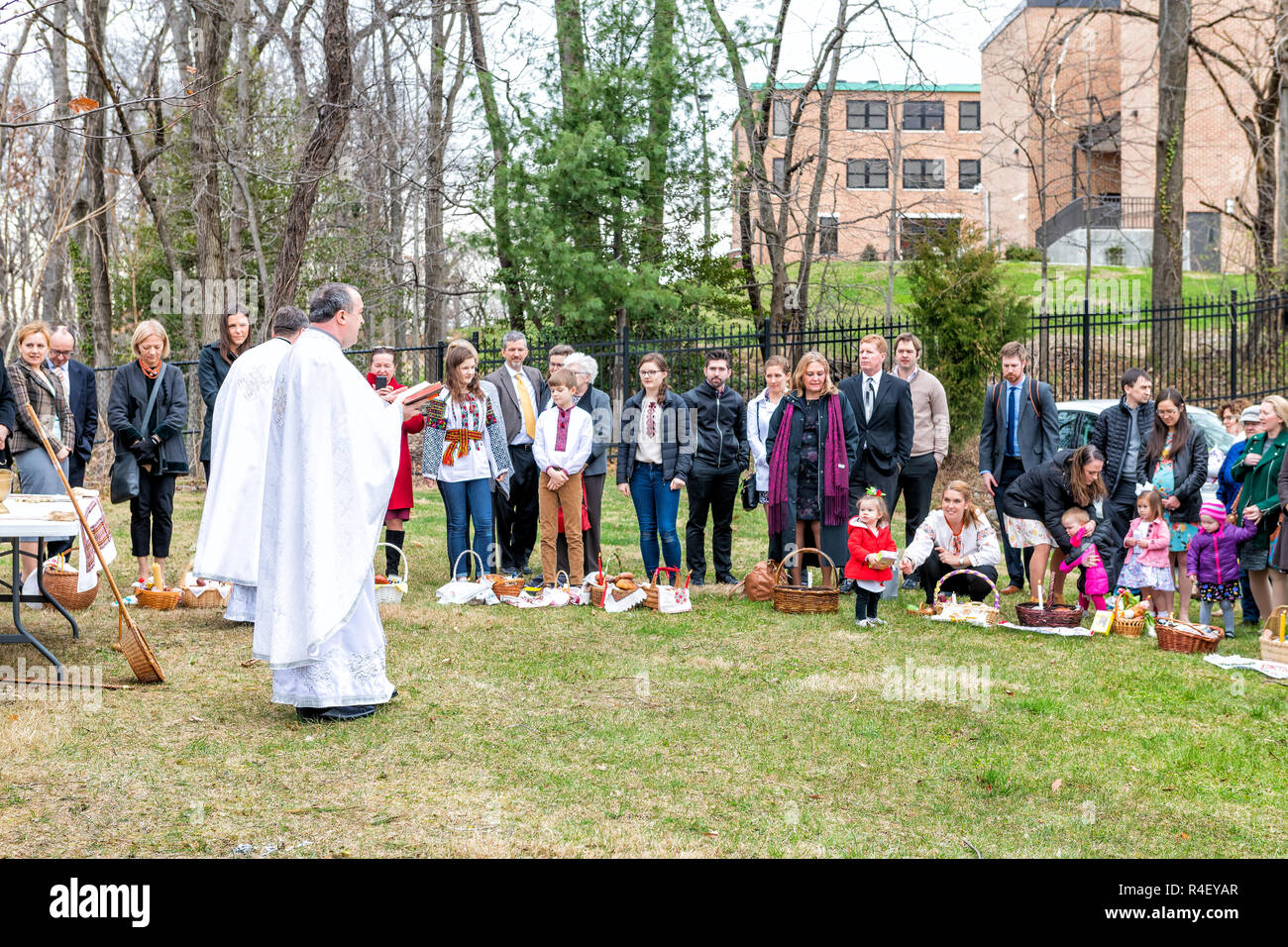 Washington DC, USA - April 1, 2018: People, children, priests praying prayer, holding bible, censer outdoors, Easter baskets for blessing at Ukrainian Stock Photo