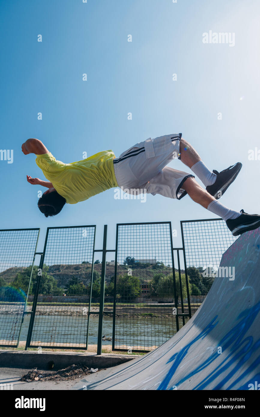 Parkour man training hard while run through obstacles in skatepark ...