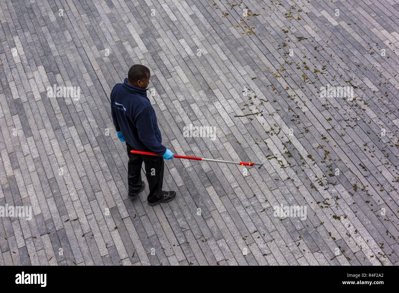 workman clearing the moss from the cracks in the pavement on a large