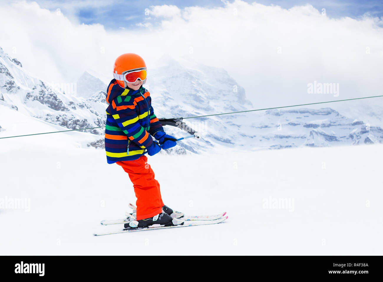 Child on a button ski lift going uphill in the mountains on a sunny