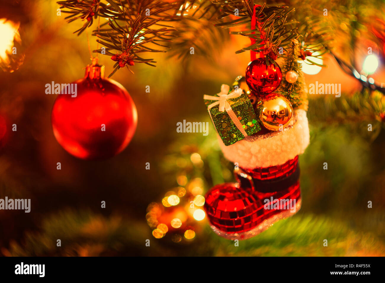 Miniature Boot filled with Presents hanging in Christmas Tree Stock Photo