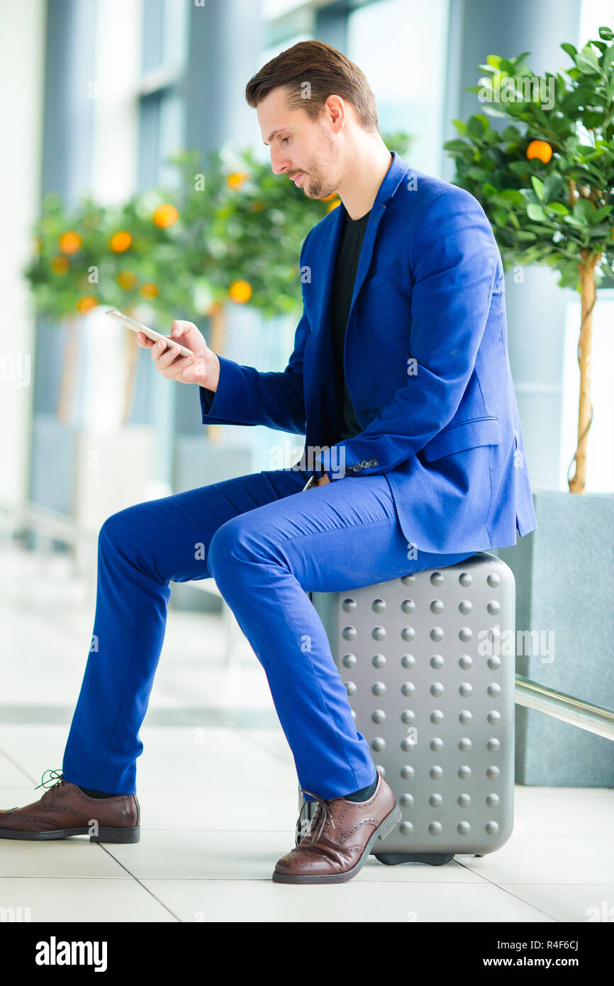 Young man with cellphone in international airport waiting for boarding