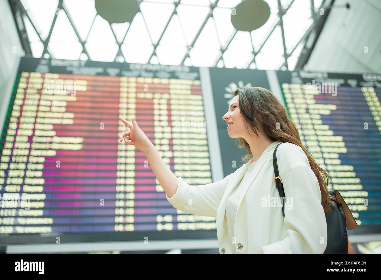 Young woman in international airport looking at the flight information ...