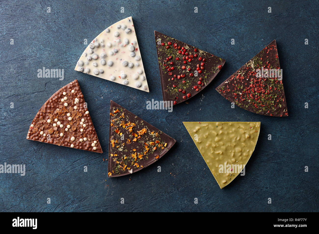 Chocolate triangle shaped pieces with diverse kinds of toppings on blue background, top view Stock Photo