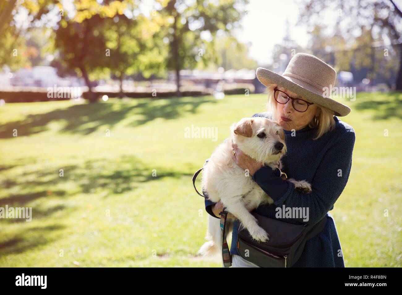 A Mature Women Kissing a Dog In Park Stock Photo