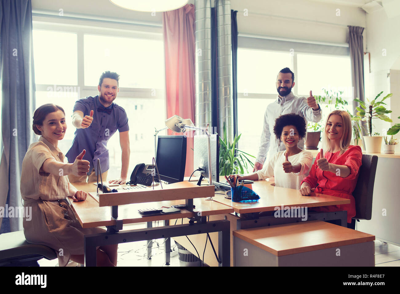 happy creative team showing thumbs up in office Stock Photo - Alamy