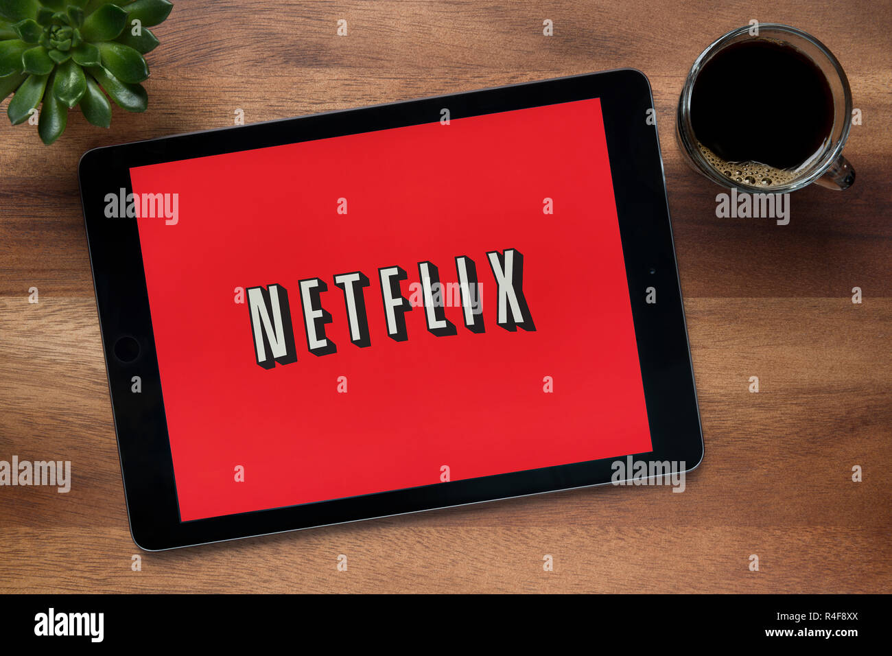 The website of Netflix is seen on an iPad tablet, on a wooden table along with an espresso coffee and a house plant (Editorial use only). Stock Photo