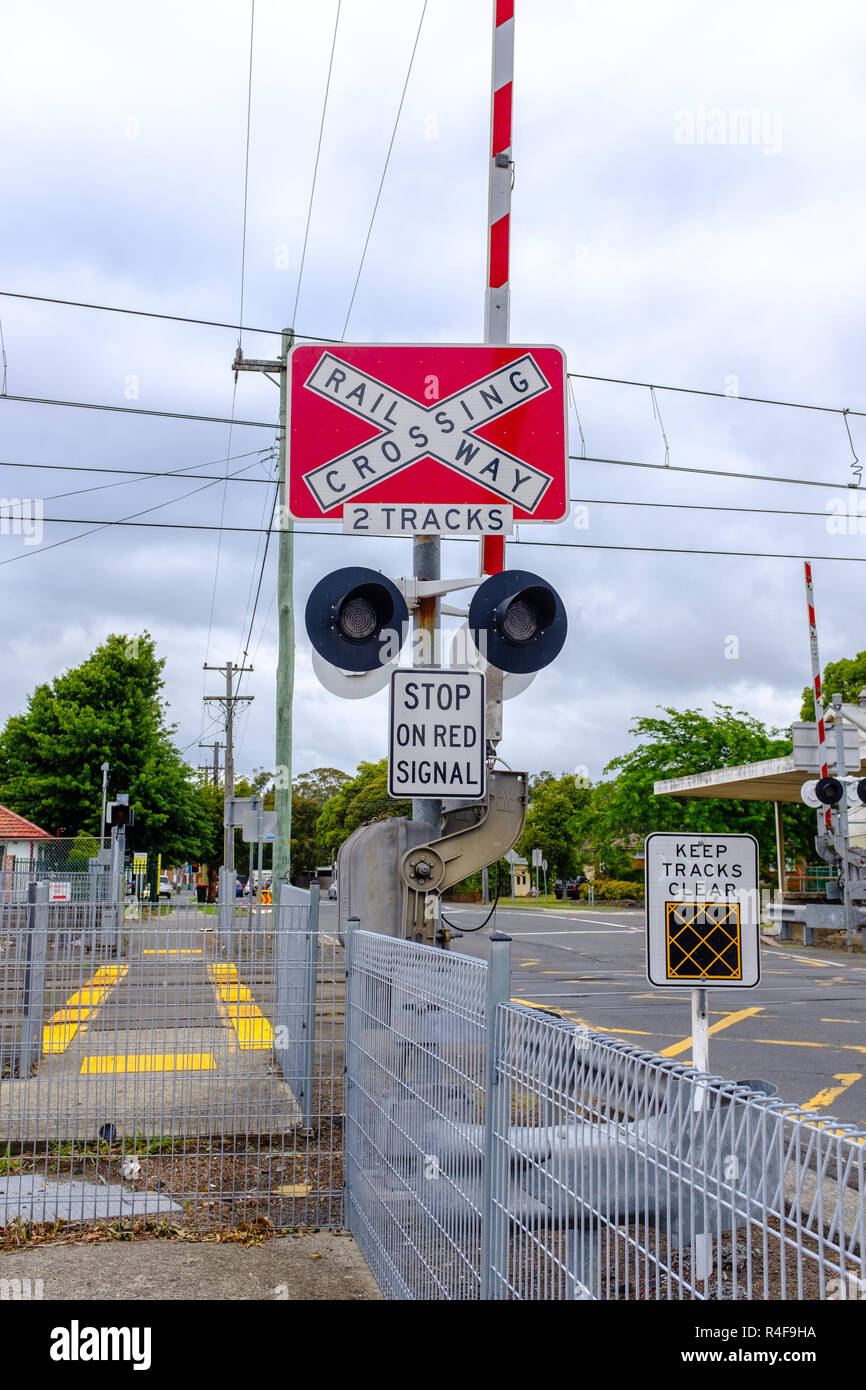 Australian railway crossing red with white cross waning sign on road, with keep tracks clear, stop at red on signal signs, NSW, Australia Stock Photo