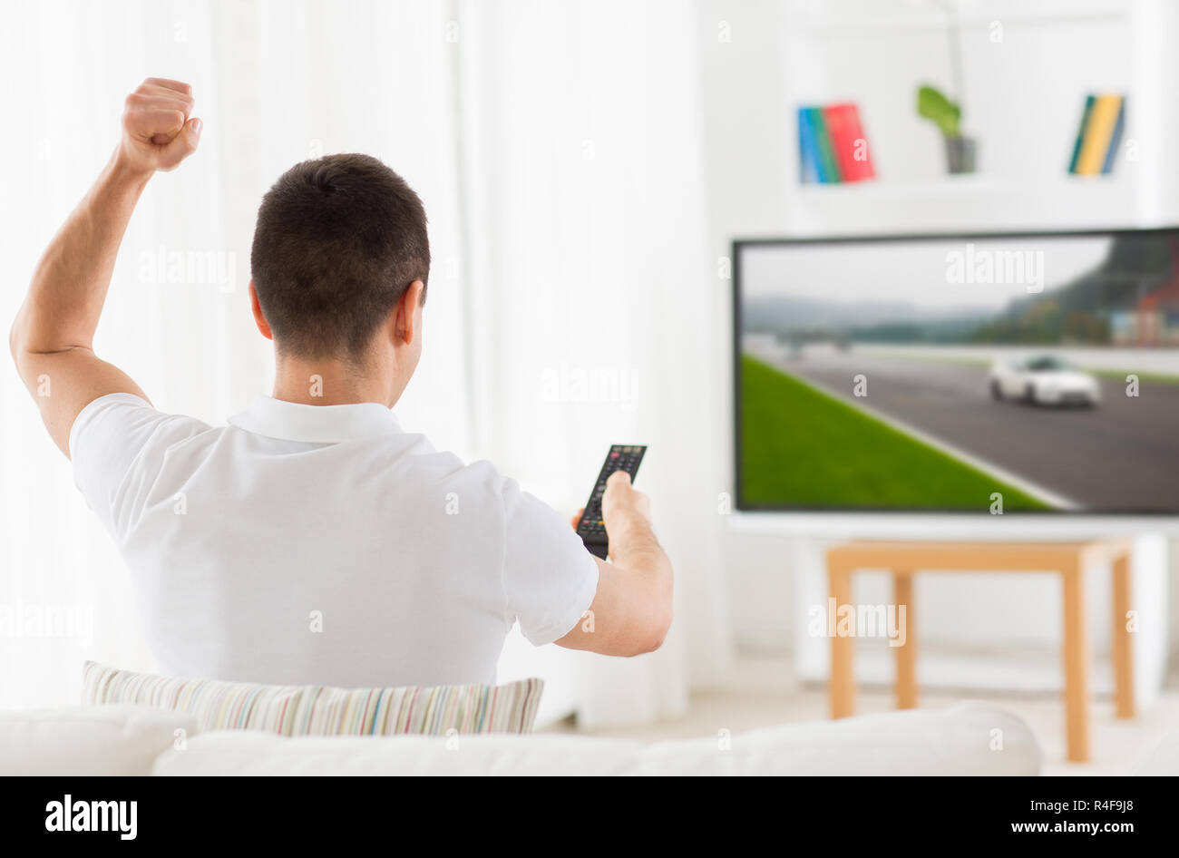 man with remote watching motorsports on tv at home Stock Photo Alamy