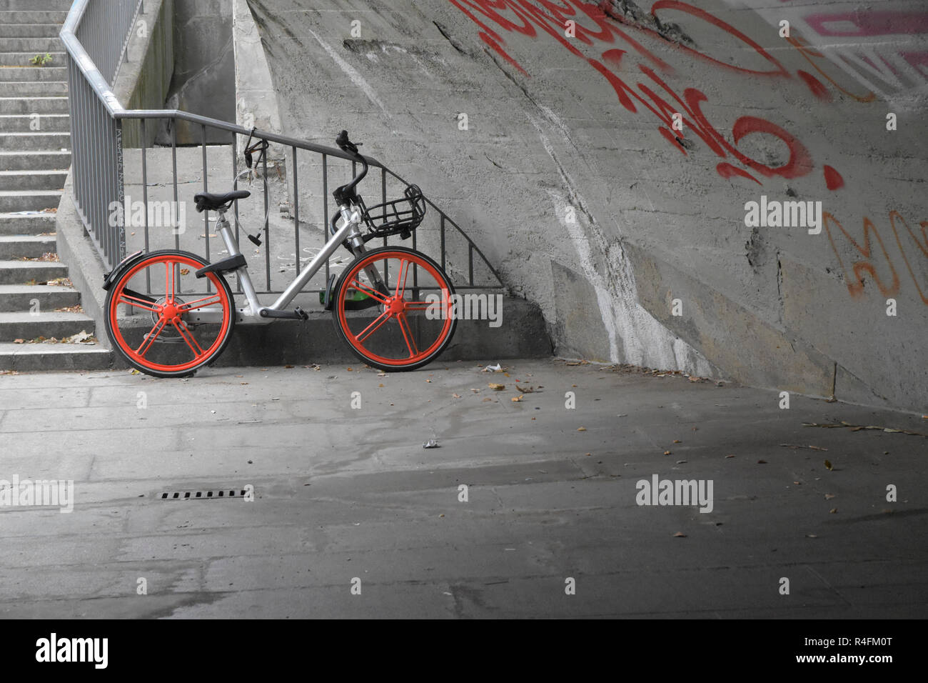 bicycle with red wheels under a grey concrete bridge, copy space Stock Photo