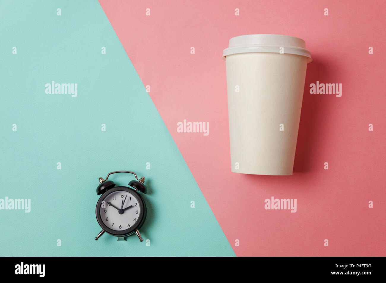Simply flat lay design paper coffee cup and alarm clock on blue pink pastel colorful trendy background. Takeaway drink and breakfast beverage. Good mo Stock Photo