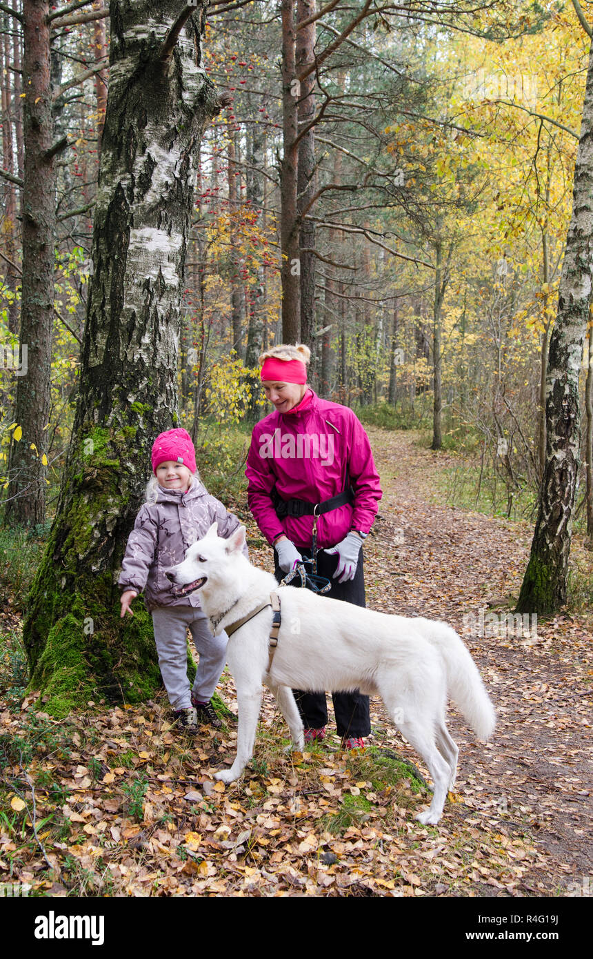 Granny with her granddaughter and a dog walk in autumn Park Stock Photo