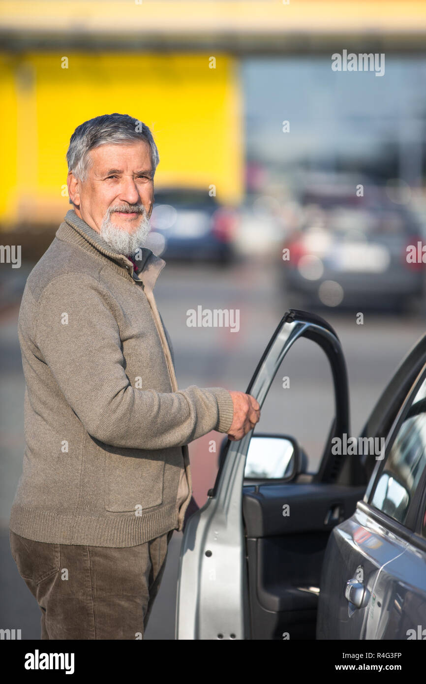 Senior driver getting in his car in a parking lot(color toned image  shallow DOF) Stock Photo