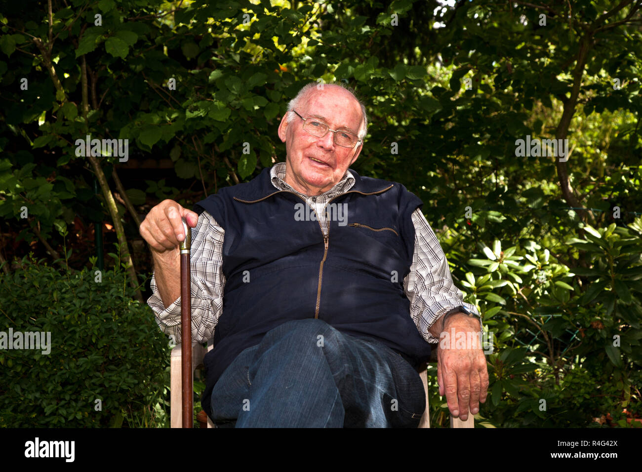 portrait of elderly man sitting happy in his garden Stock Photo