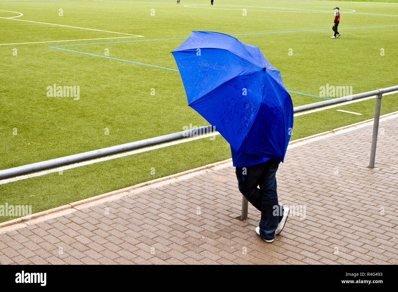 man under umbrella is watching the football game Stock Photo Alamy