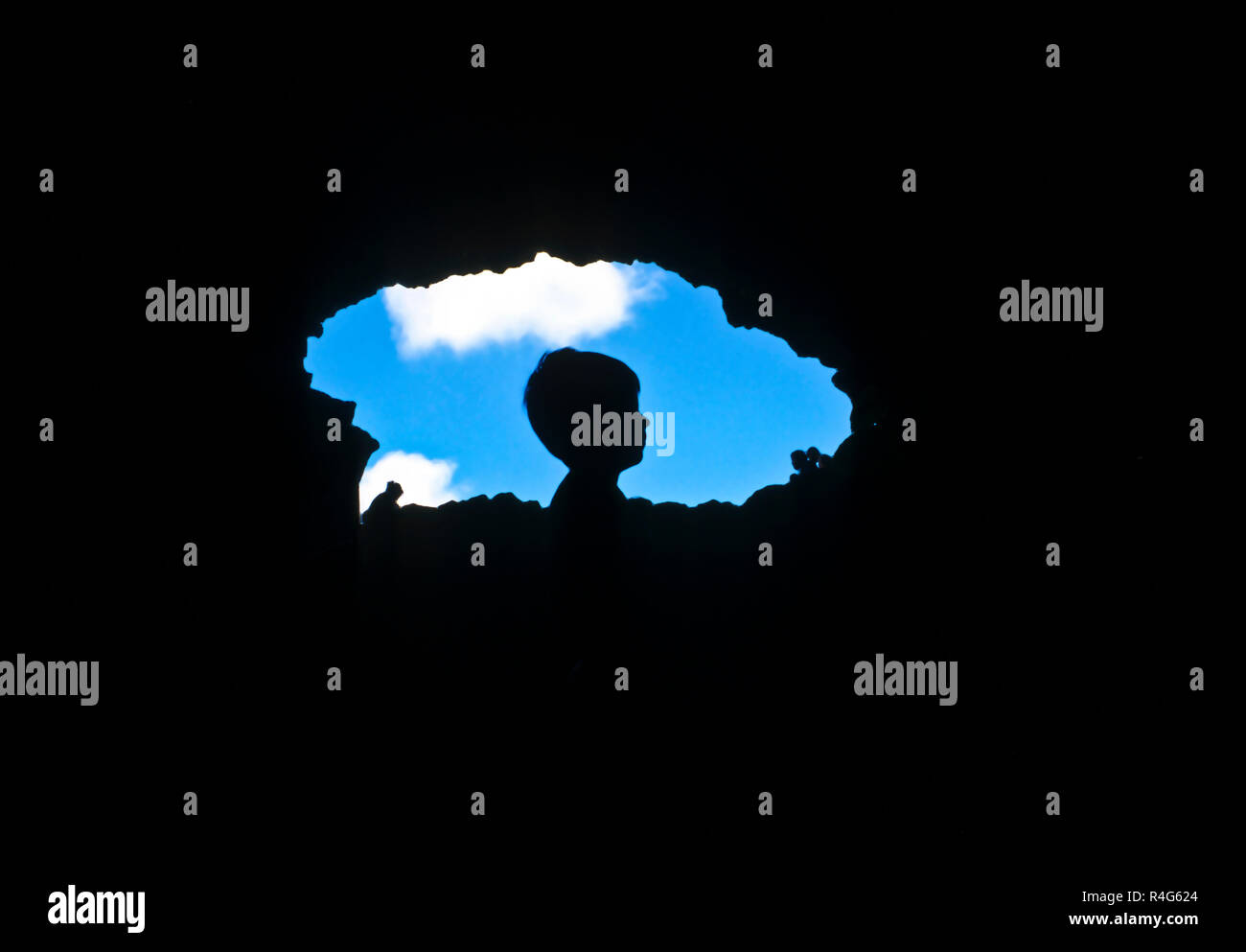 profile of young boy against blue sky seen from cave Stock Photo - Alamy