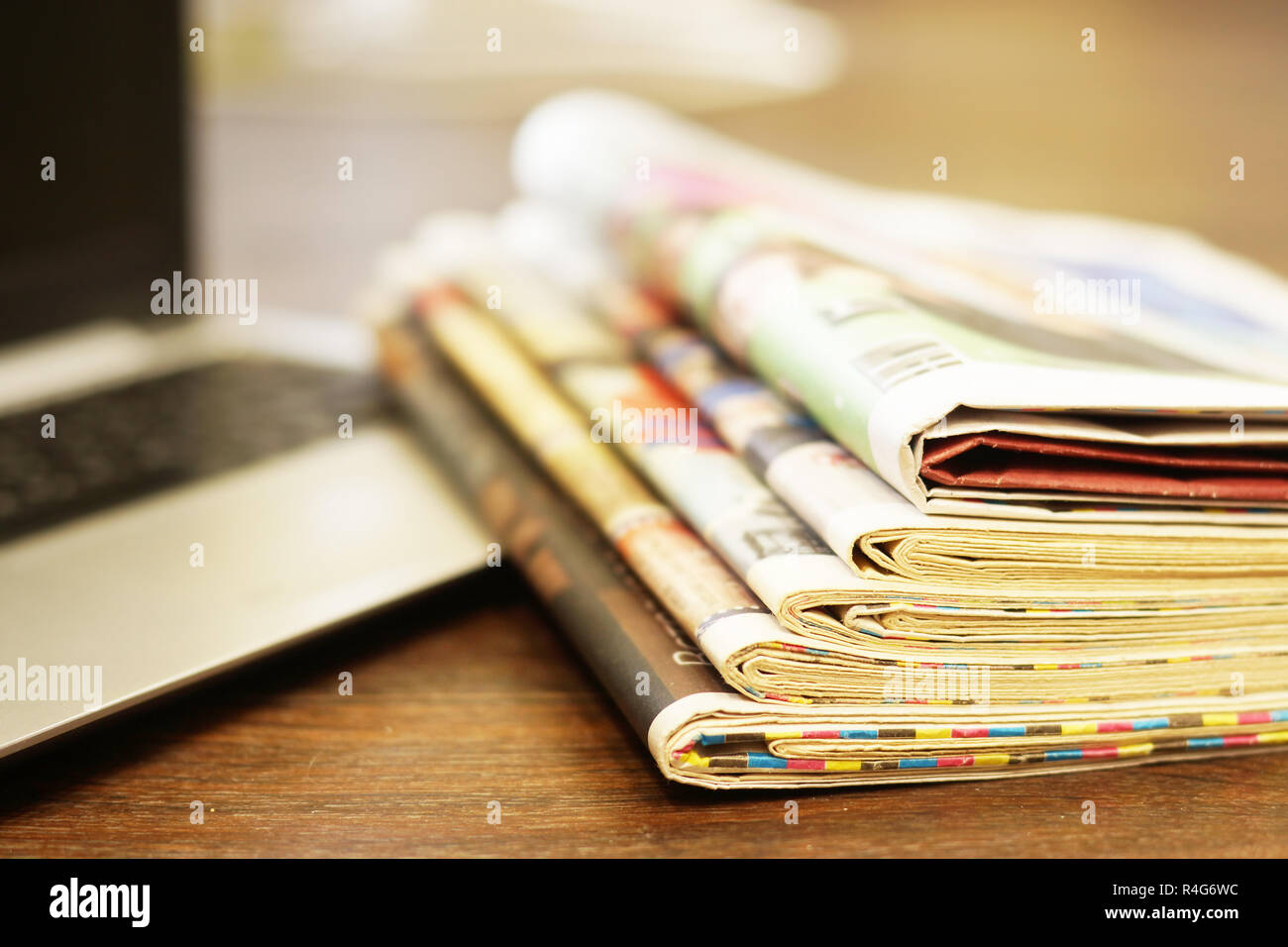 Newspapers and laptop. Pile of daily papers with news on computer. Pages with headlines, articles folded and stacked on keypad of electronic device Stock Photo