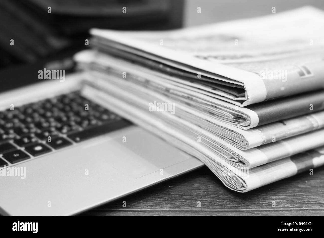 Newspapers and laptop. Pile of daily papers with news on computer. Pages with headlines, articles folded and stacked on keypad of electronic device Stock Photo