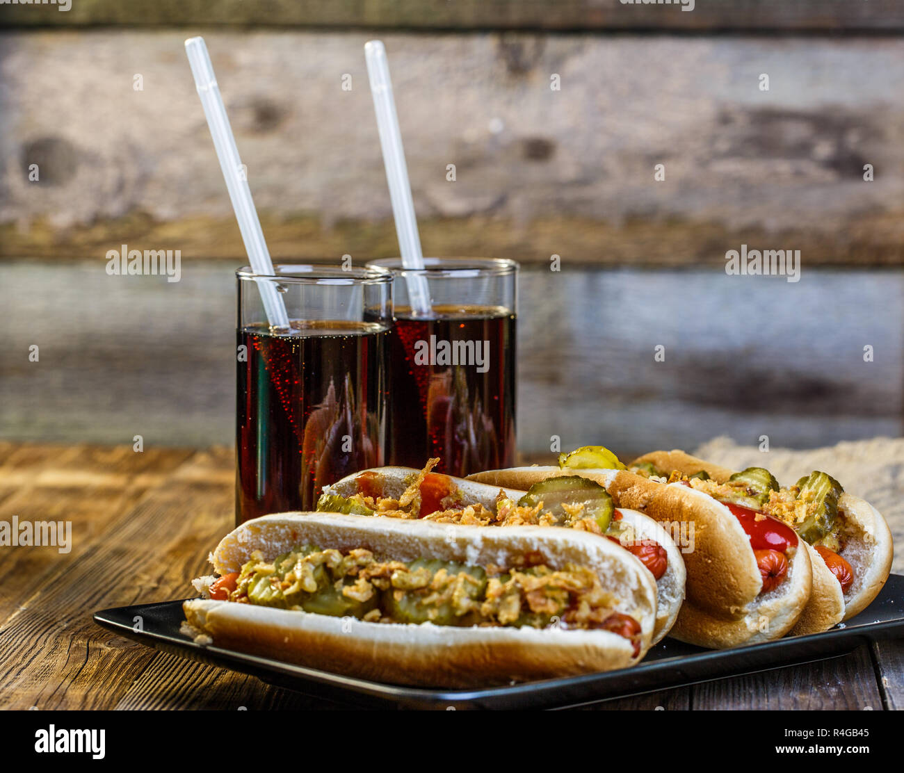 American hot dog with pickles,onions, ketchup, mustard and two soda