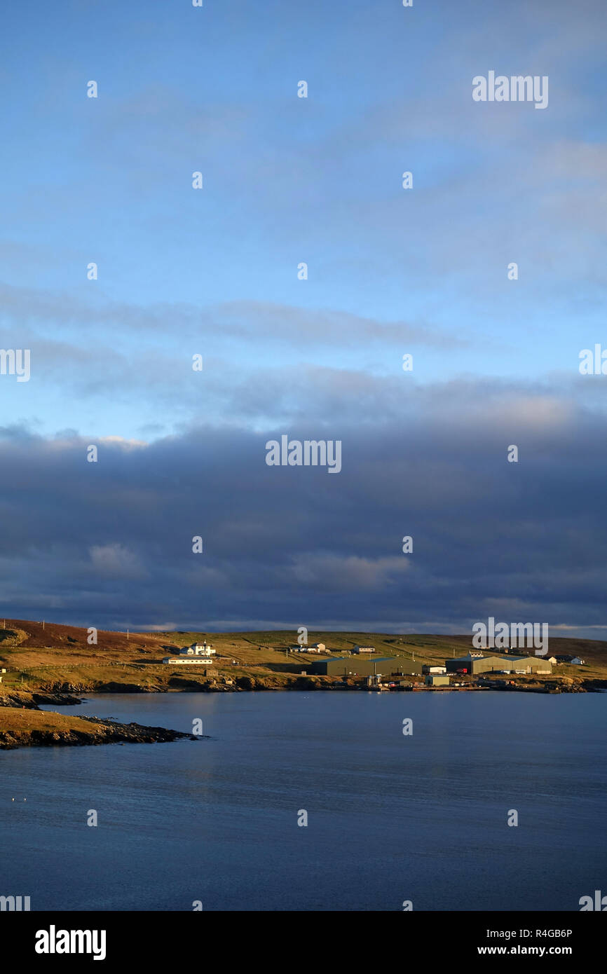Low winter light in Hoswick Sandwick Shetland with homes around the cliffs and coastline of the village Stock Photo