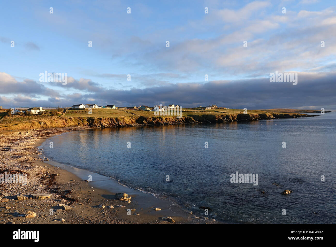 Low winter light in Hoswick Sandwick Shetland with homes around the cliffs and coastline of the village Stock Photo