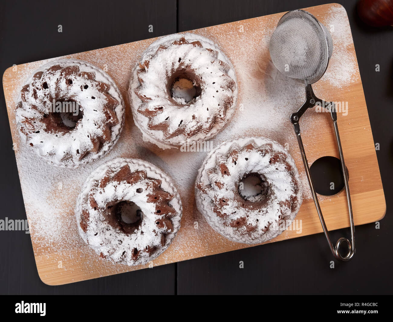 Miniature Chestnut Bundt Cakes with Chocolate Chips on a bamboo cutting board, on a dark brown background Stock Photo