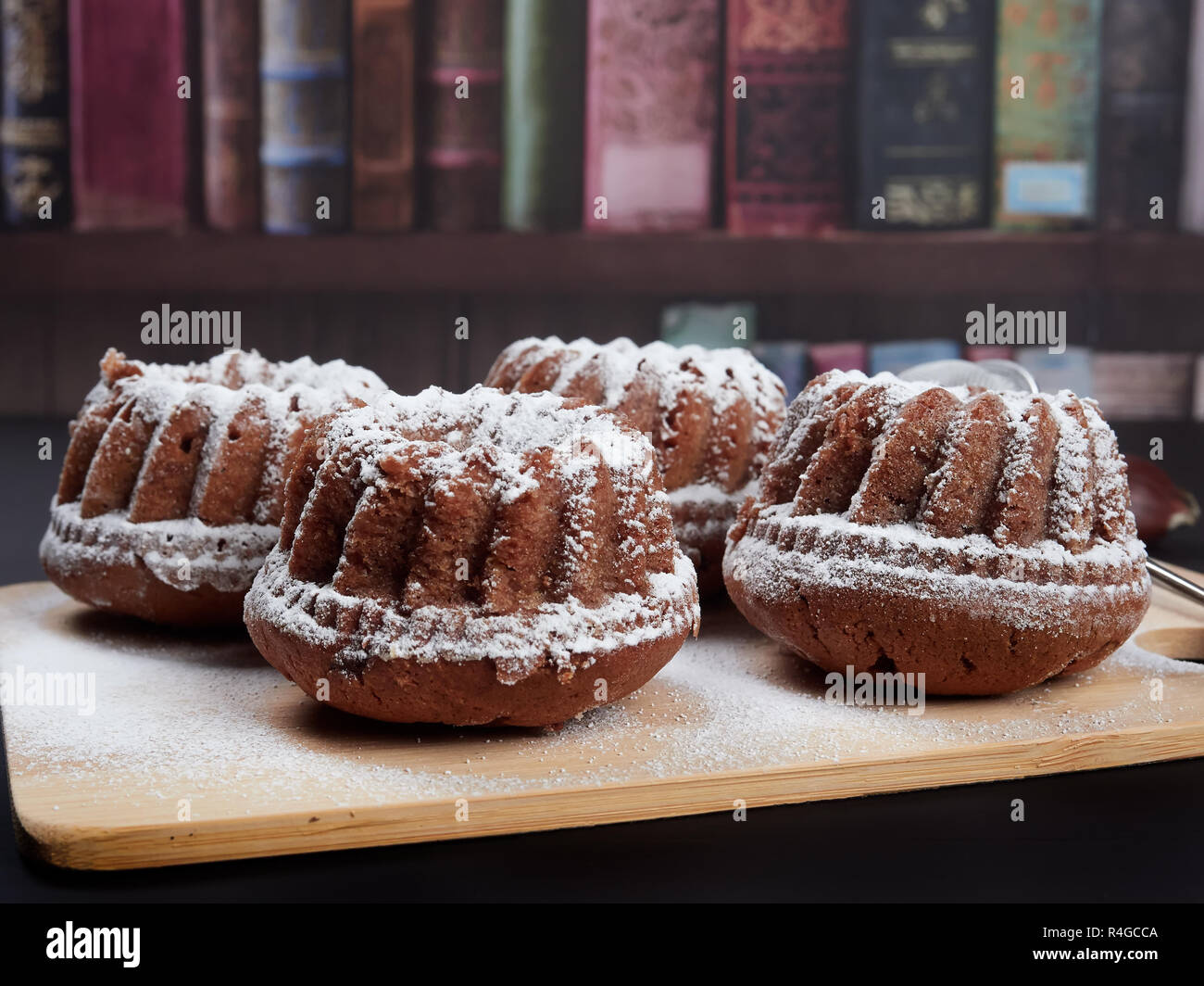 Miniature Chestnut Bundt Cakes with Chocolate Chips on a bamboo cutting board, on a dark brown background Stock Photo